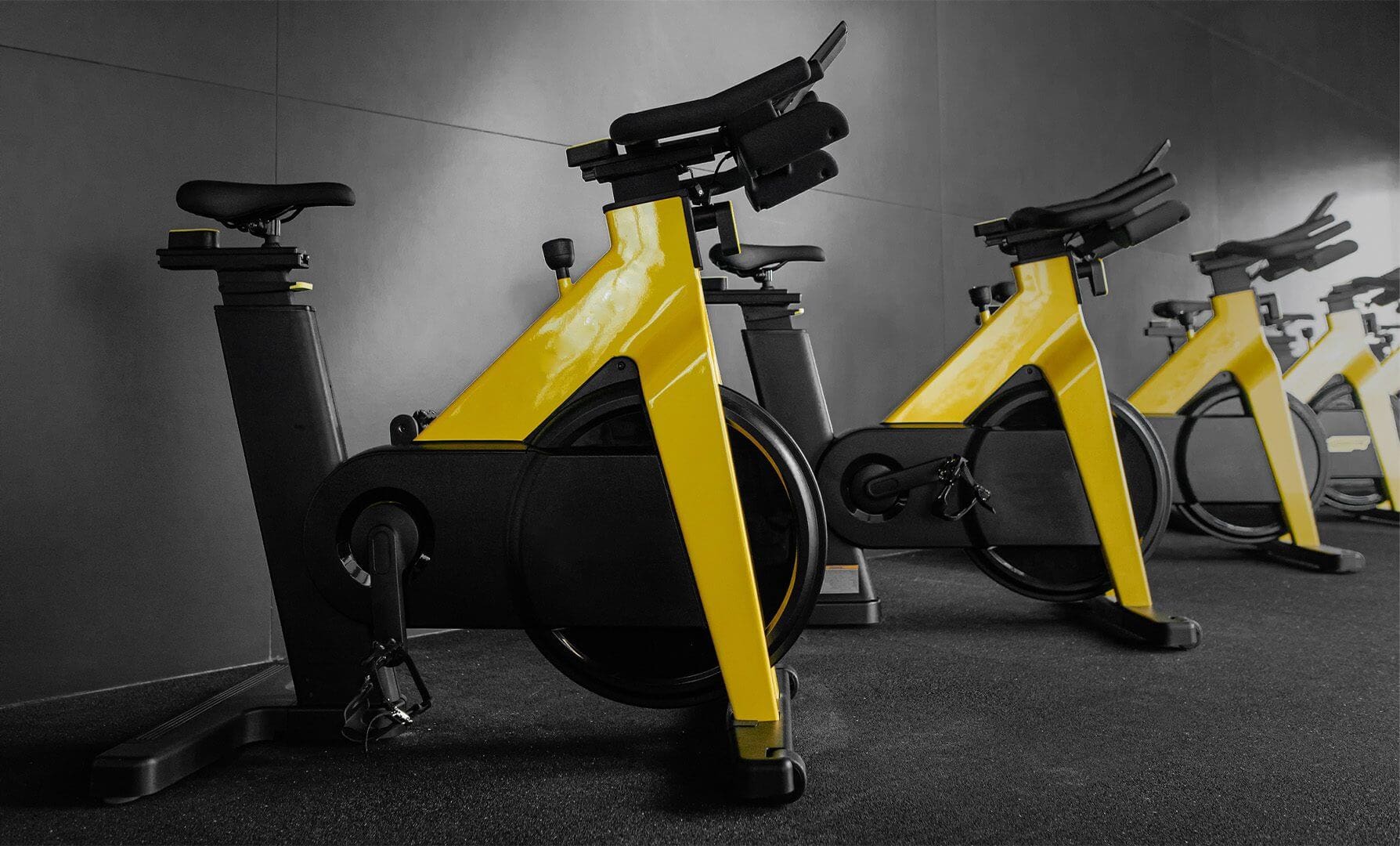 Yellow stationary bikes in a gym setting.