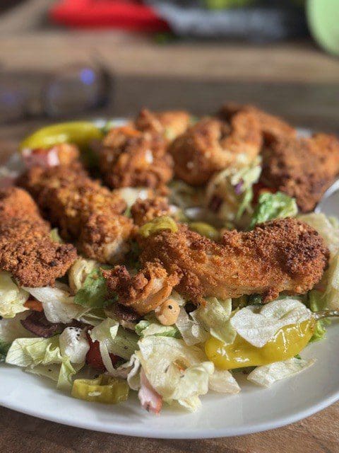 Fried chicken pieces served on a bed of fresh lettuce and pickles.